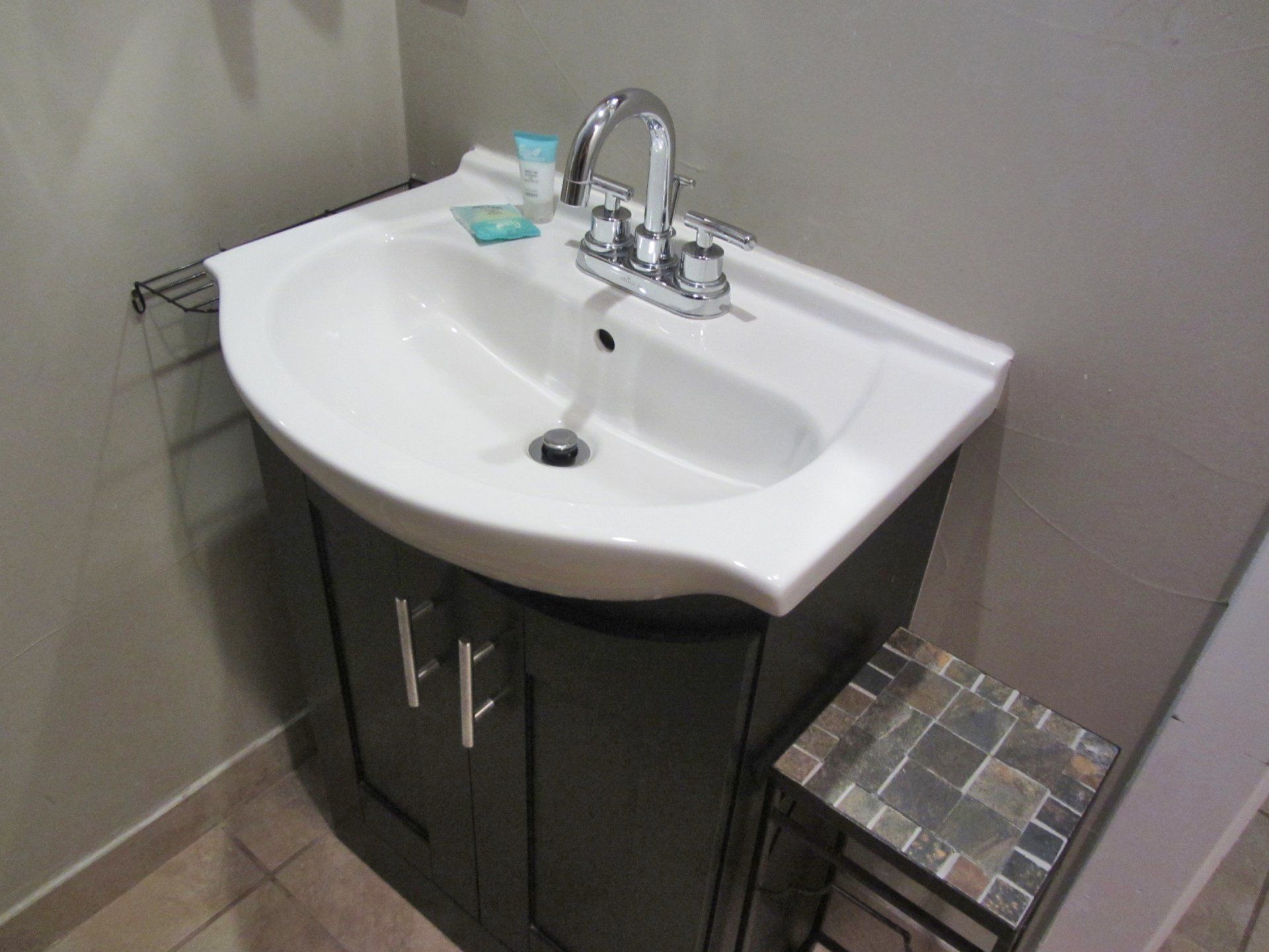 A bathroom sink with a stool next to it