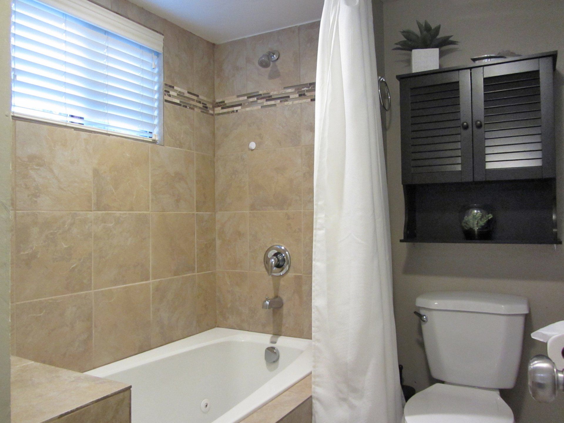 A bathroom with a tub , toilet and window