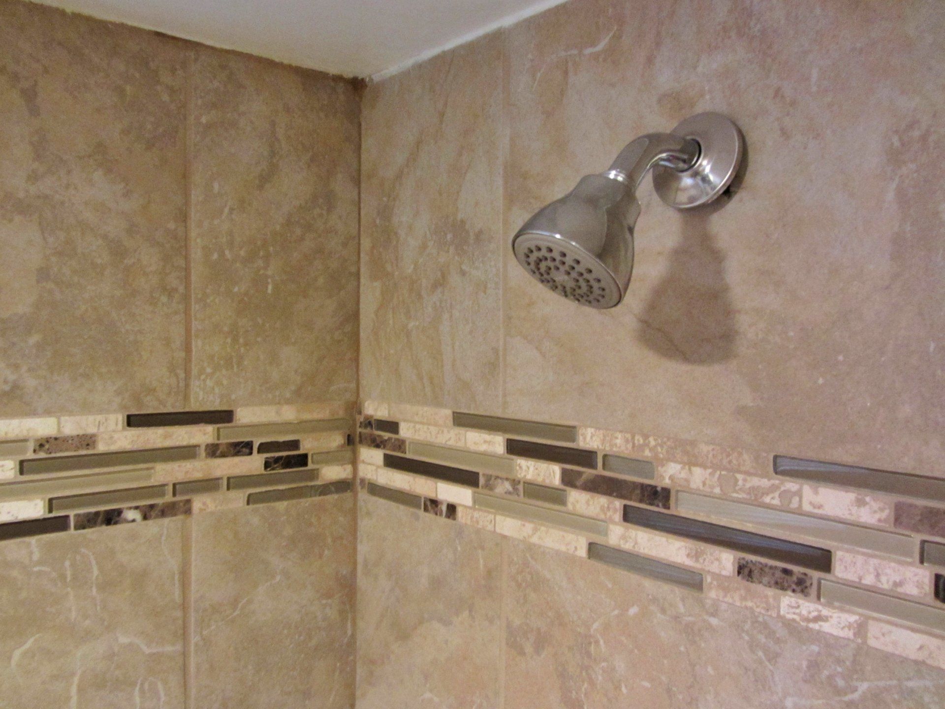 A shower head is hanging on a tiled wall in a bathroom.