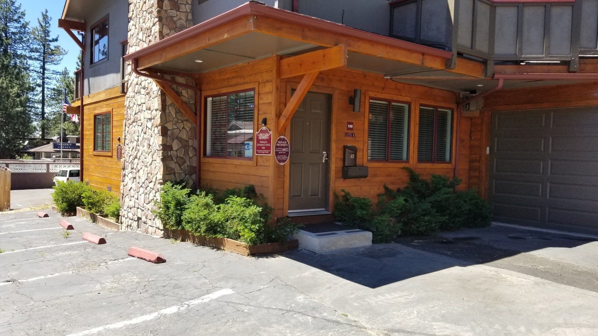 A building with a wooden porch and a parking lot in front of it.