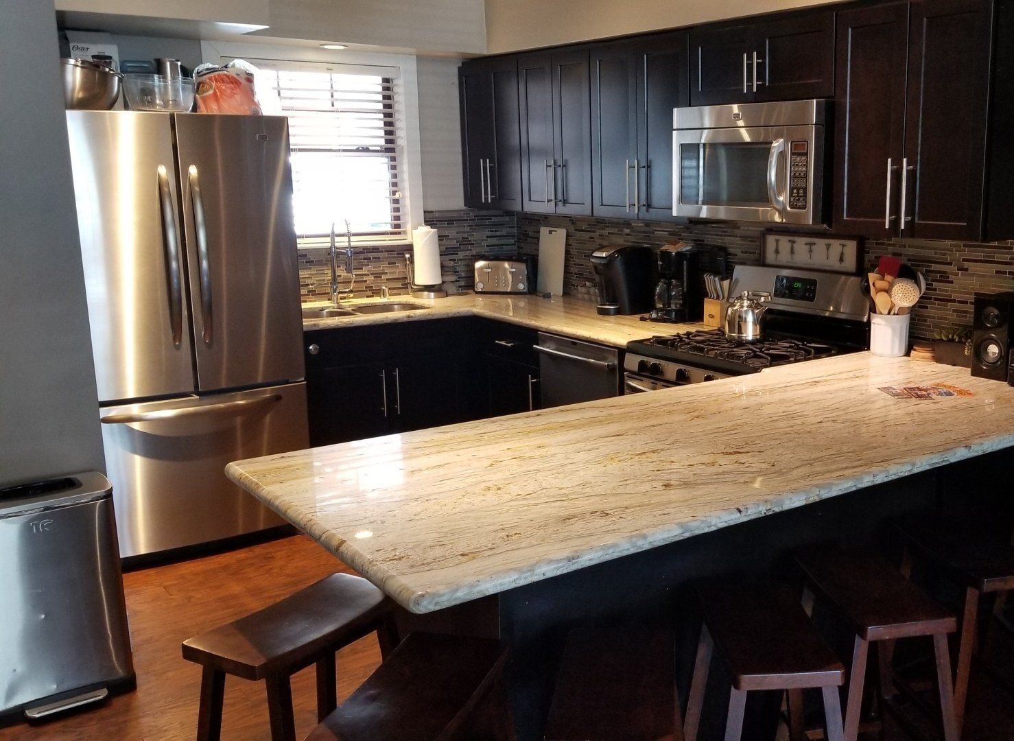 Kitchen with stainless steel appliances, dark cabinets, granite countertops, and a breakfast bar with stools.