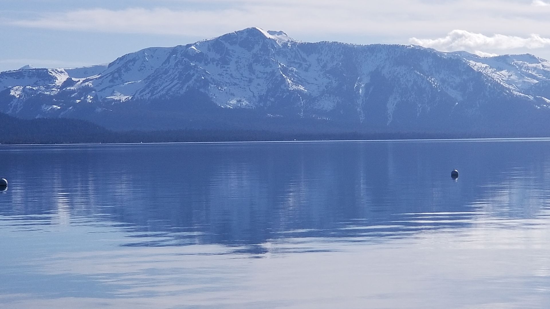 A lake with snow covered mountains in the background