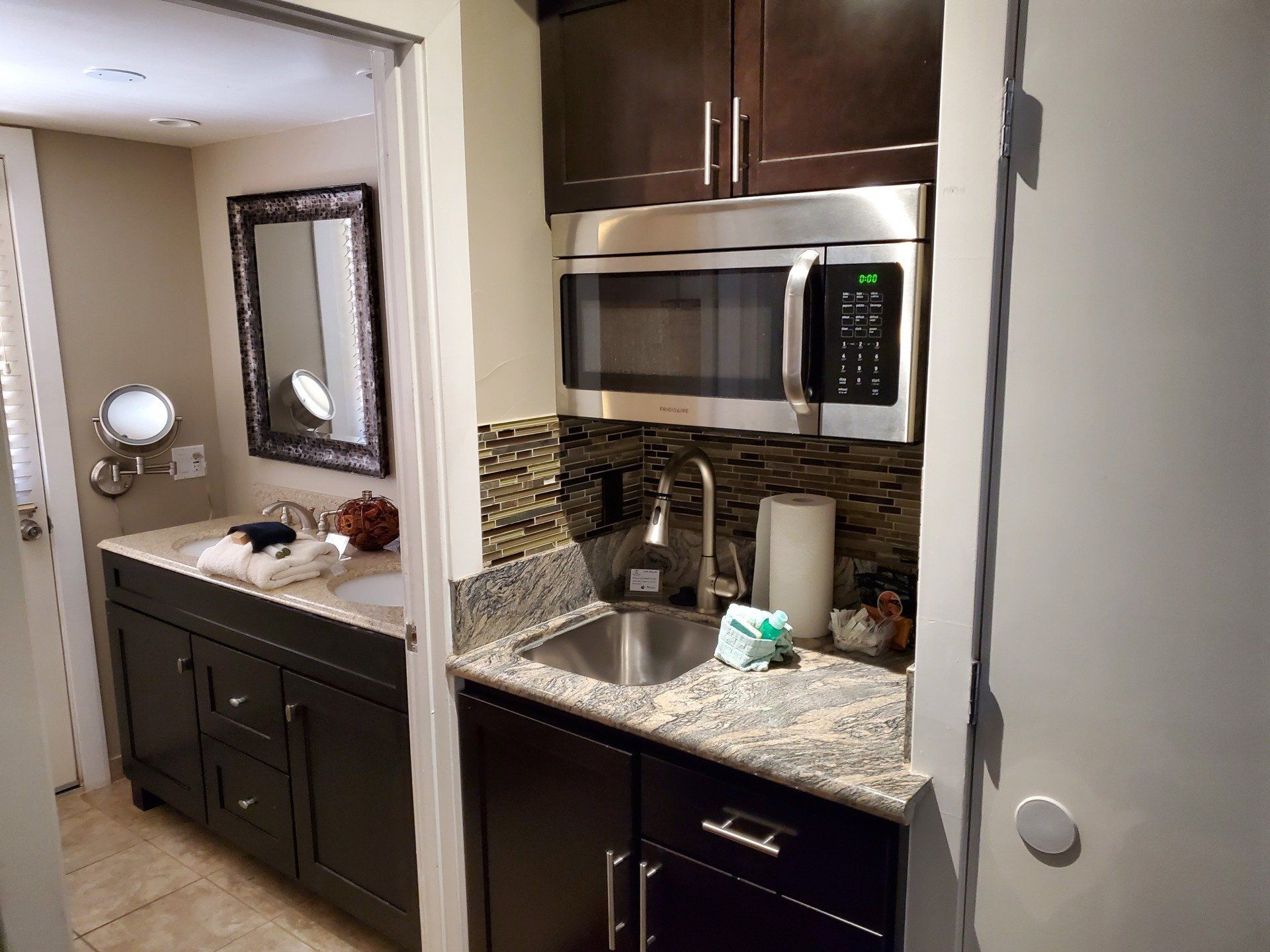 A kitchen with a sink , microwave , and mirror