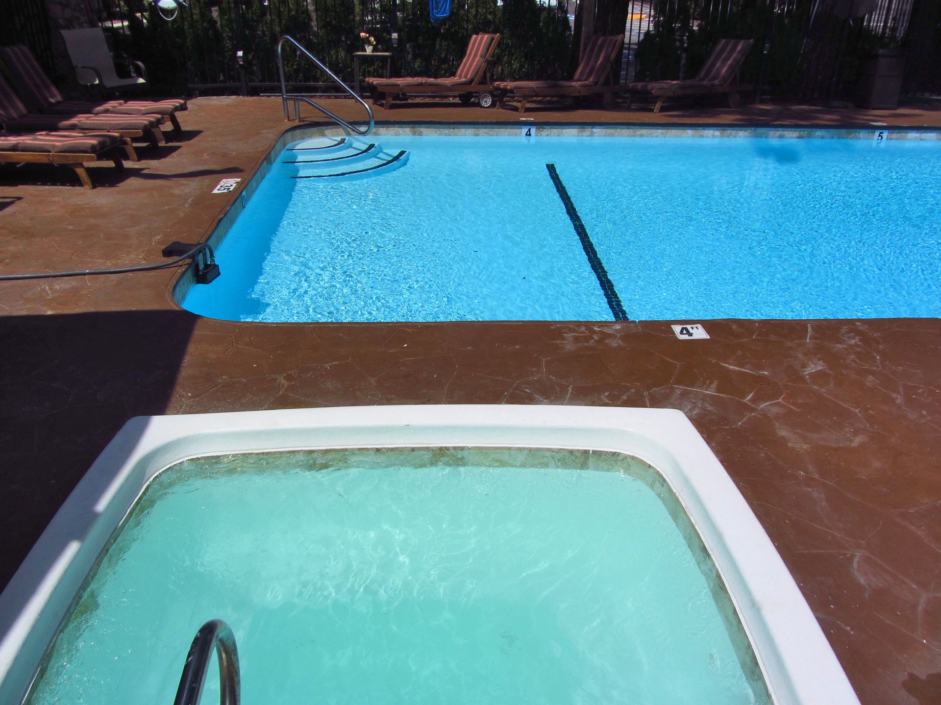 A hot tub sits next to a large swimming pool