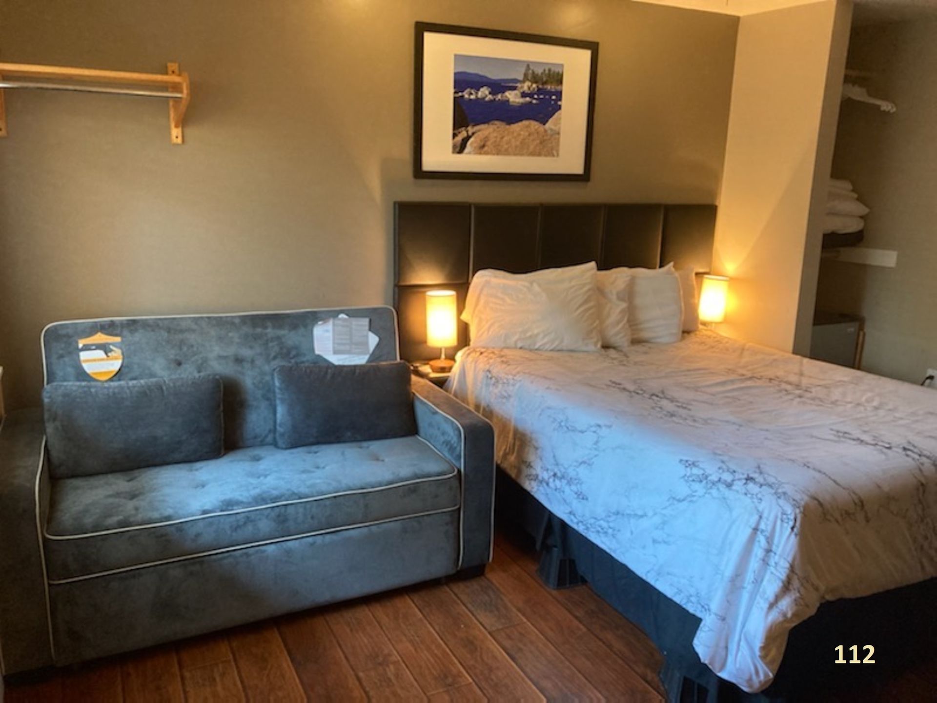 A hotel room with a bed , couch and a picture on the wall.