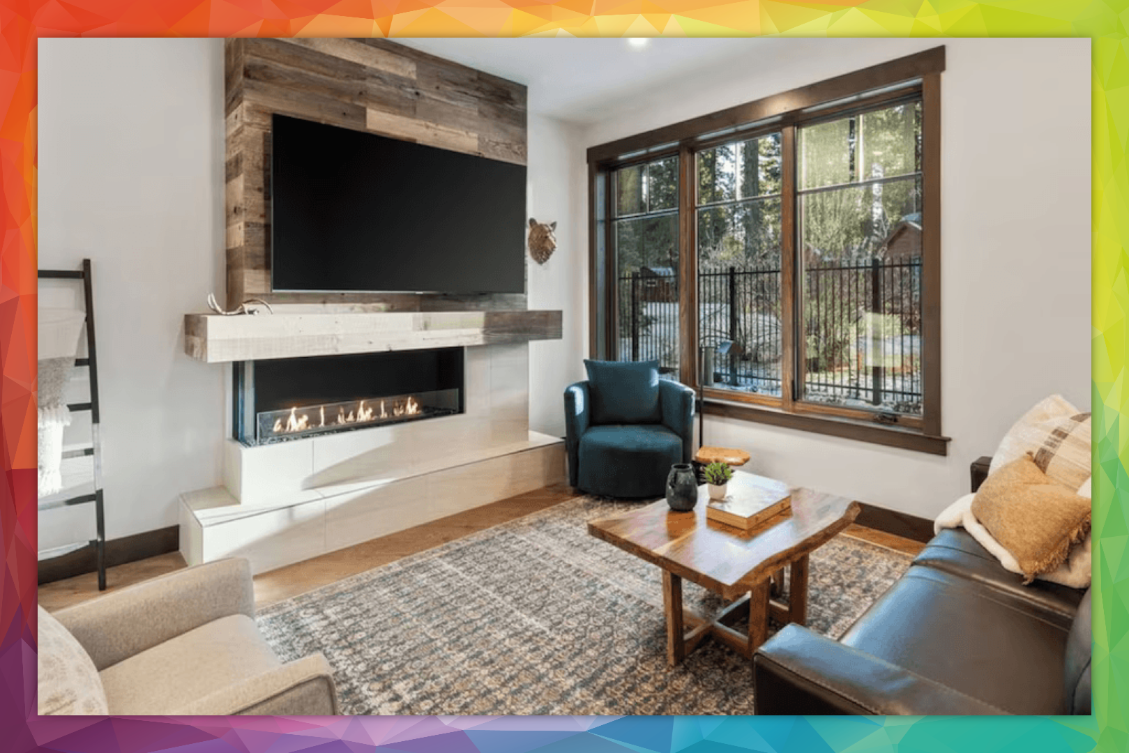 Cozy living room with fireplace, TV, and large windows looking out to trees. Furnished with a leather couch and armchairs.