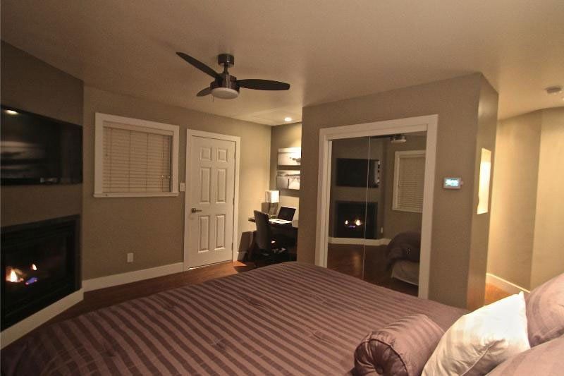 A bedroom with a ceiling fan and a fireplace