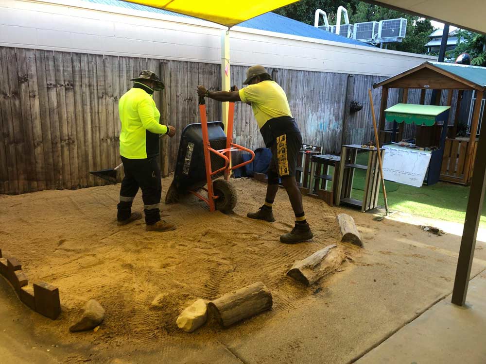 Two Workers Putting Sand On The Floor — NQ Parks and Gardens in Cairns, QLD