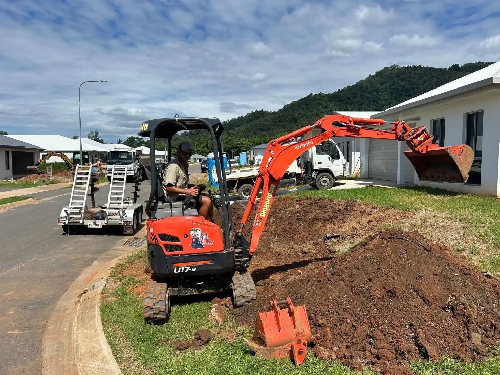 A Man Is Driving a Small Excavator on A Dirt Road — NQ Parks and Gardens in Innisfail, QLD