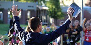 man speaking to crowd, holding a book