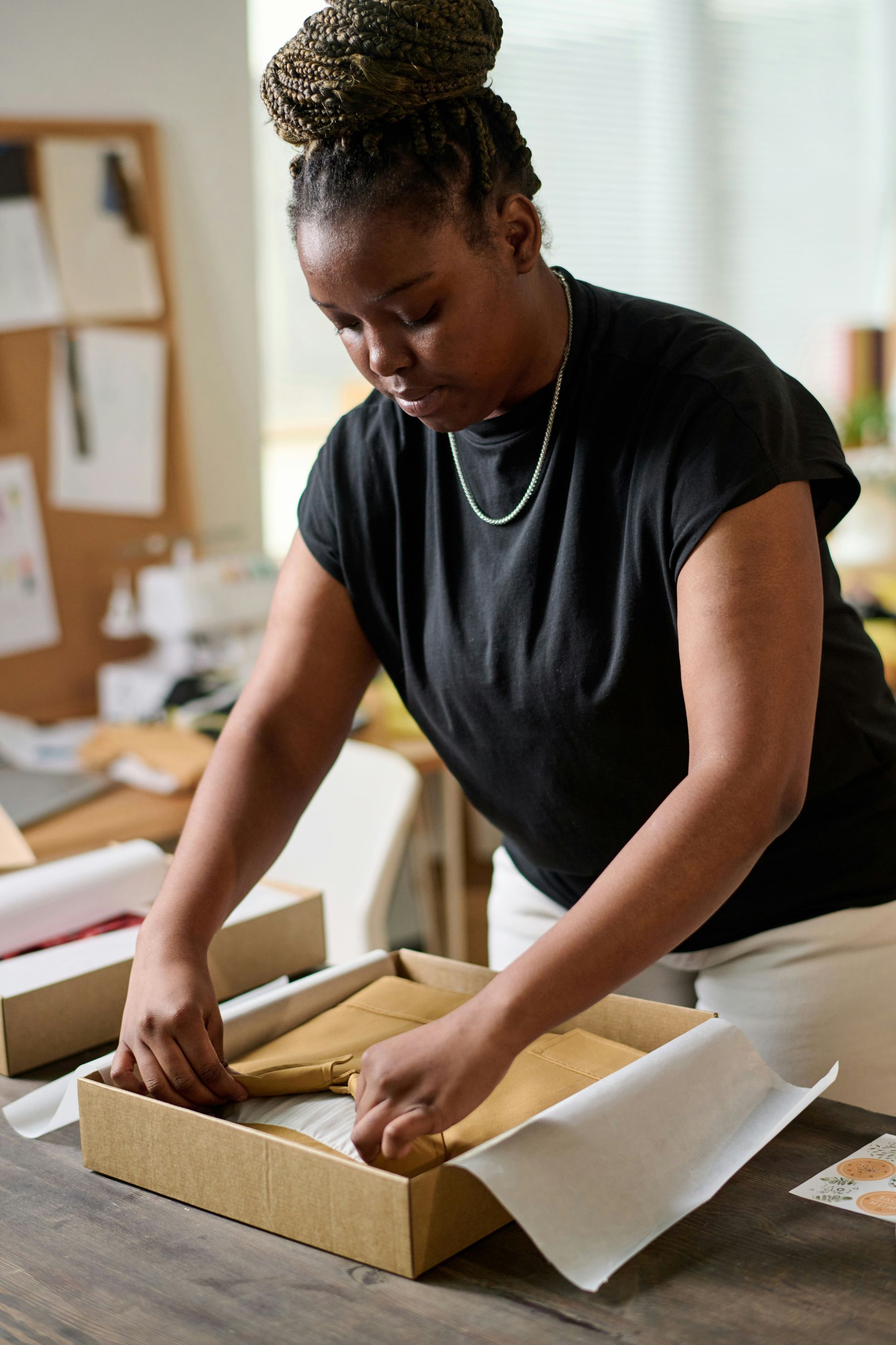 Person in a black shirt packing a cardboard box at a workspace