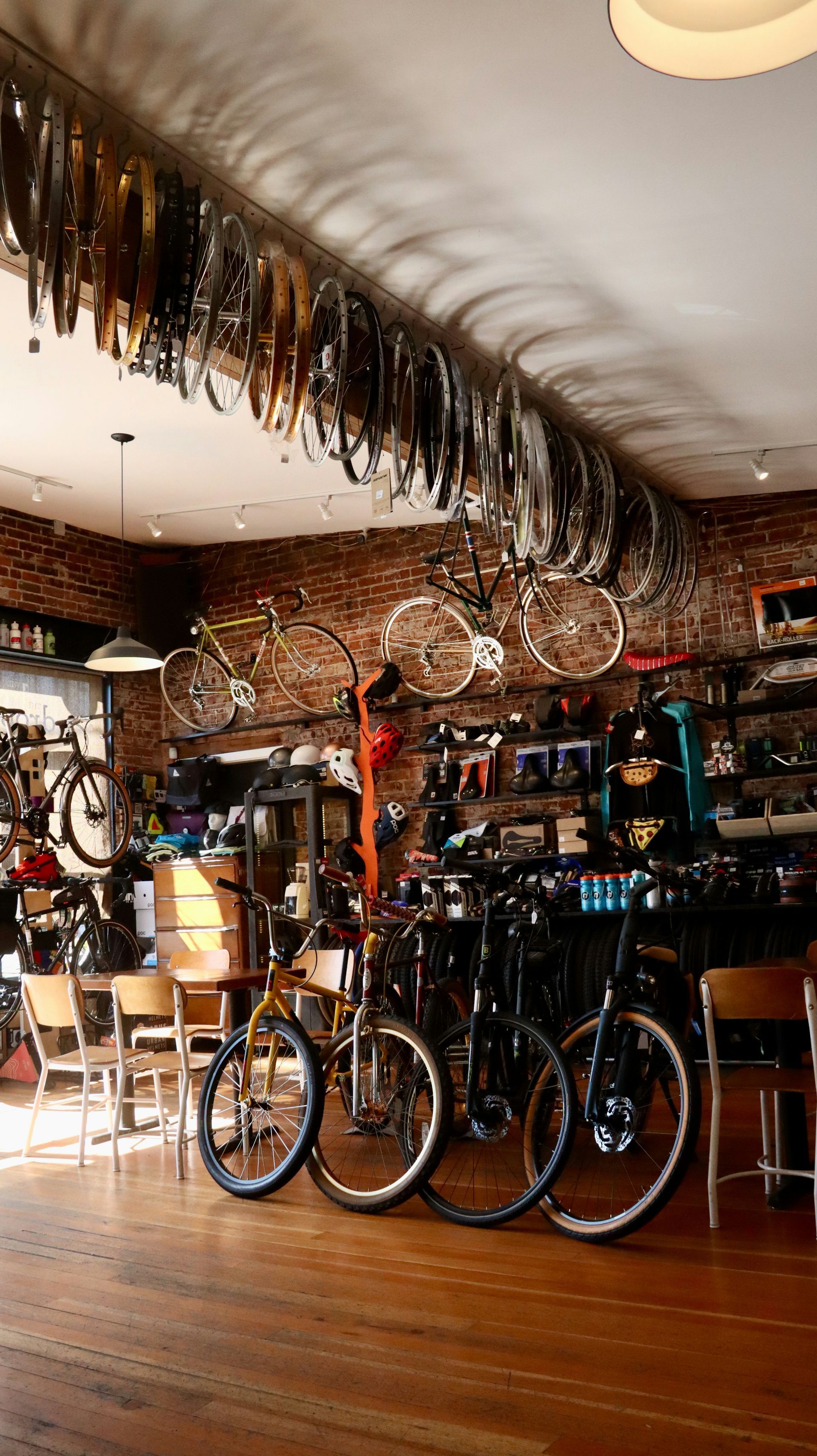 Bicycle shop interior with several bikes, racks of gear, and wooden floors under warm lighting