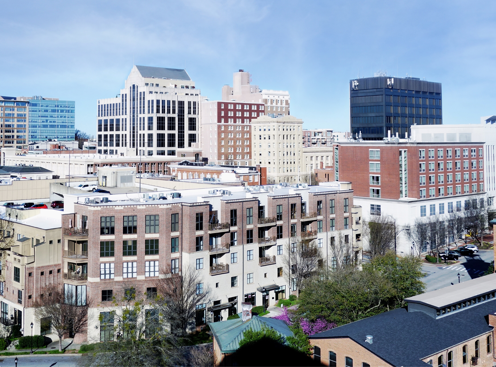 Cityscape with diverse buildings under a blue sky; brick and modern architecture.