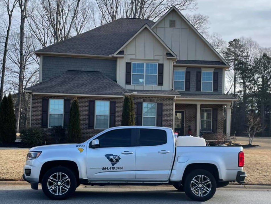 Silver truck with company logo parked in front of a two-story house.