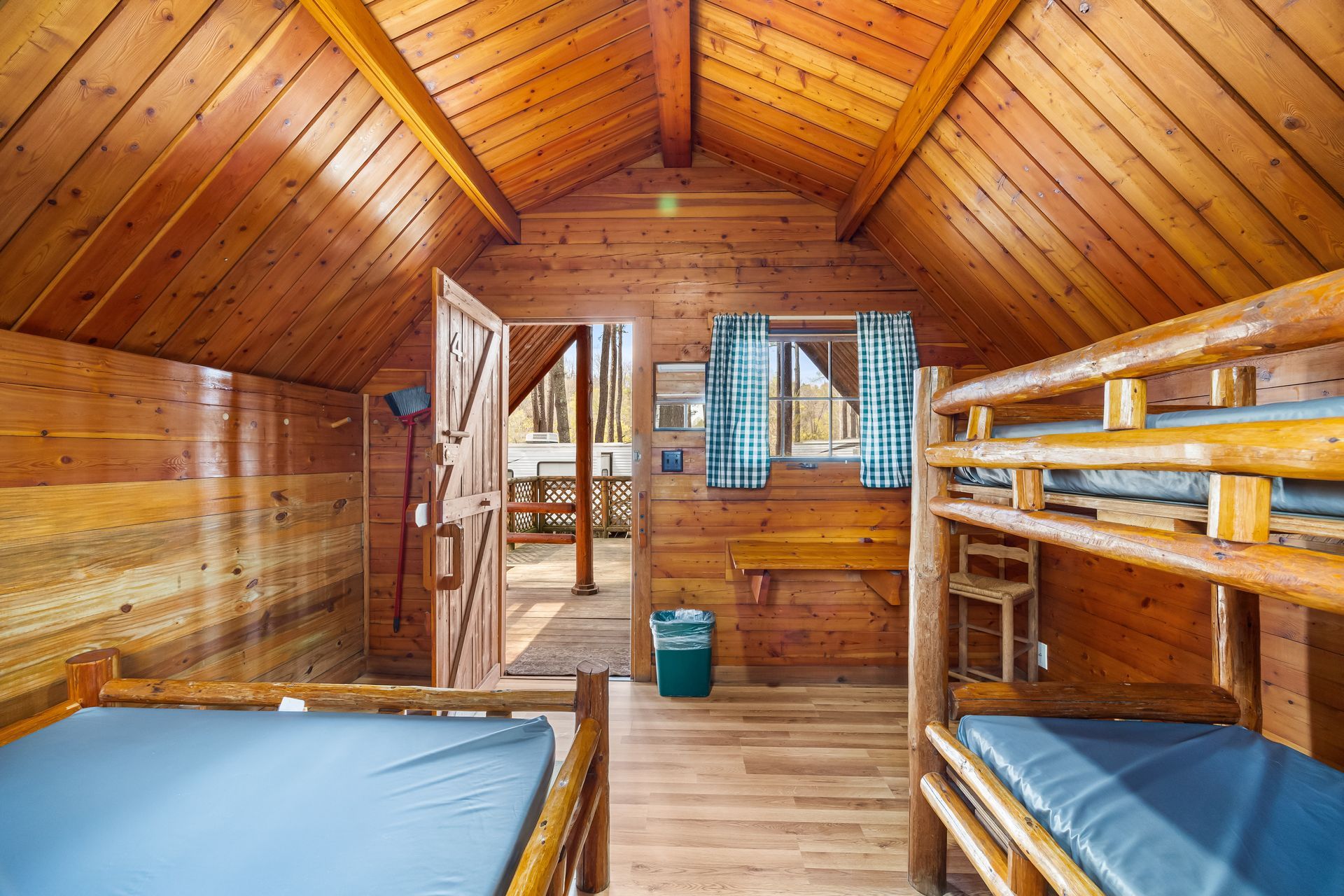A wooden cabin with bunk beds and a trash can.