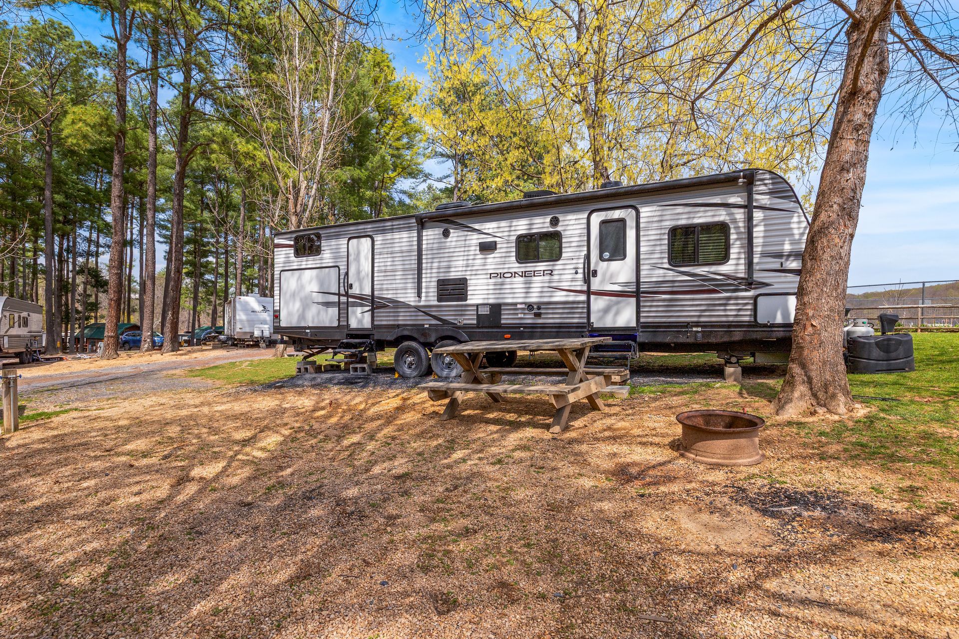 A rv is parked in a grassy area next to a tree.