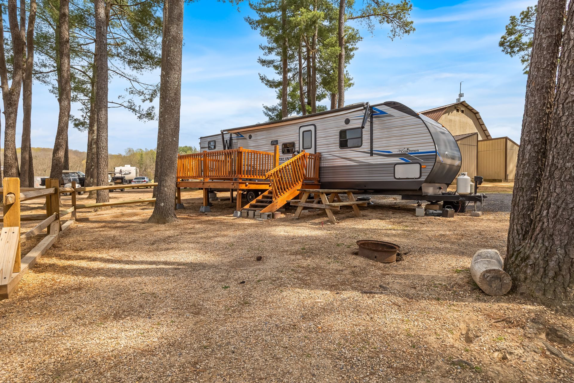 A trailer with a deck and stairs is parked in the middle of a forest.