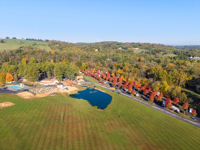 Aerial of the open field, pond and maple-lined road in fall