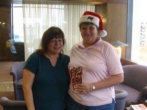 Two women wearing santa hats are posing for a picture