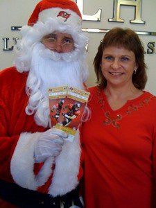 A woman is standing next to a man dressed as santa claus