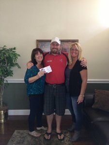 A man and two women are standing next to each other in a living room.