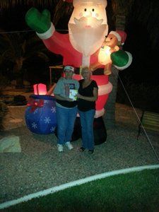 Two people standing in front of an inflatable santa claus