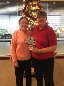 Two women are standing next to each other in front of a christmas tree.