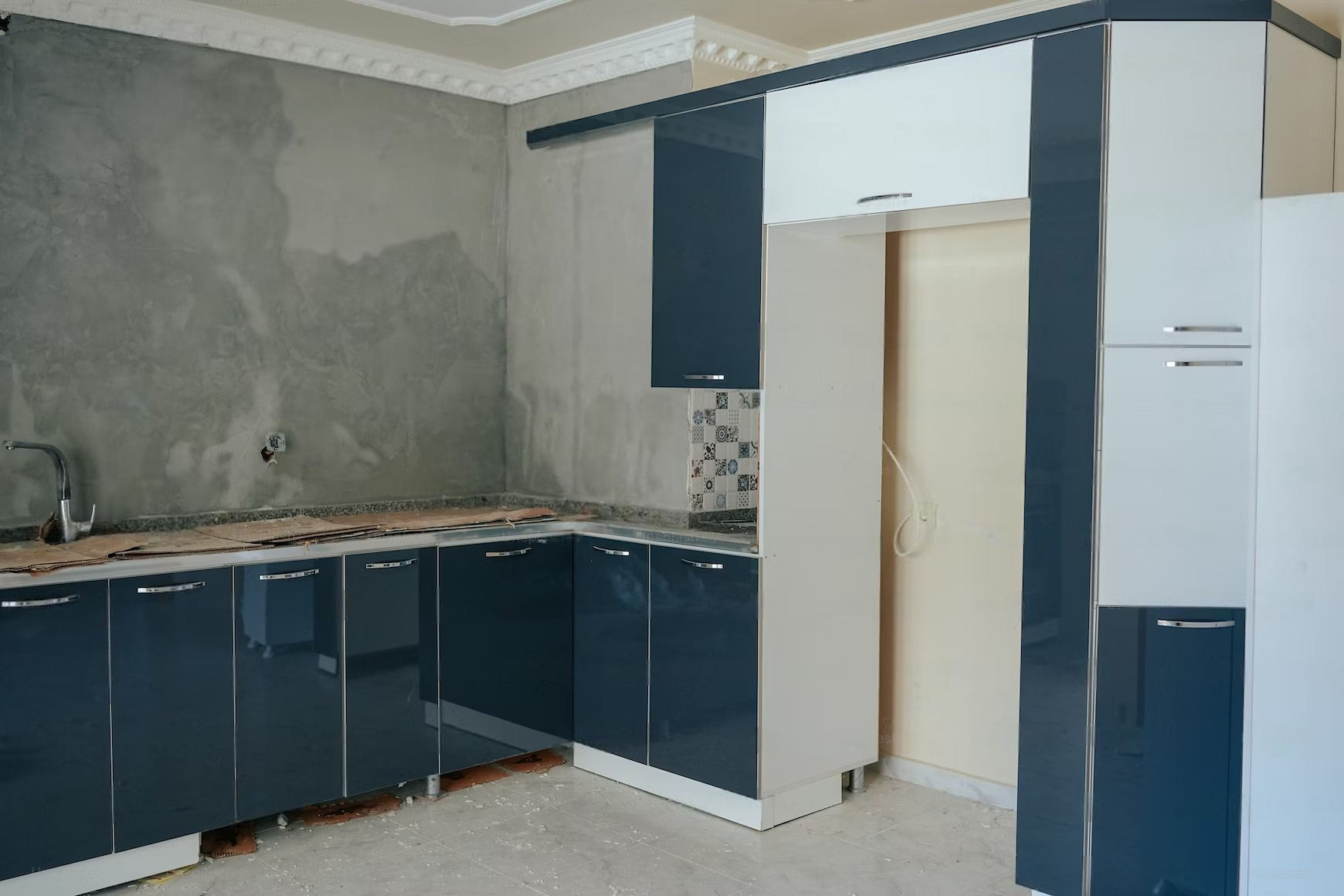 Kitchen with dark blue and white cabinets, unfinished walls, and countertop.