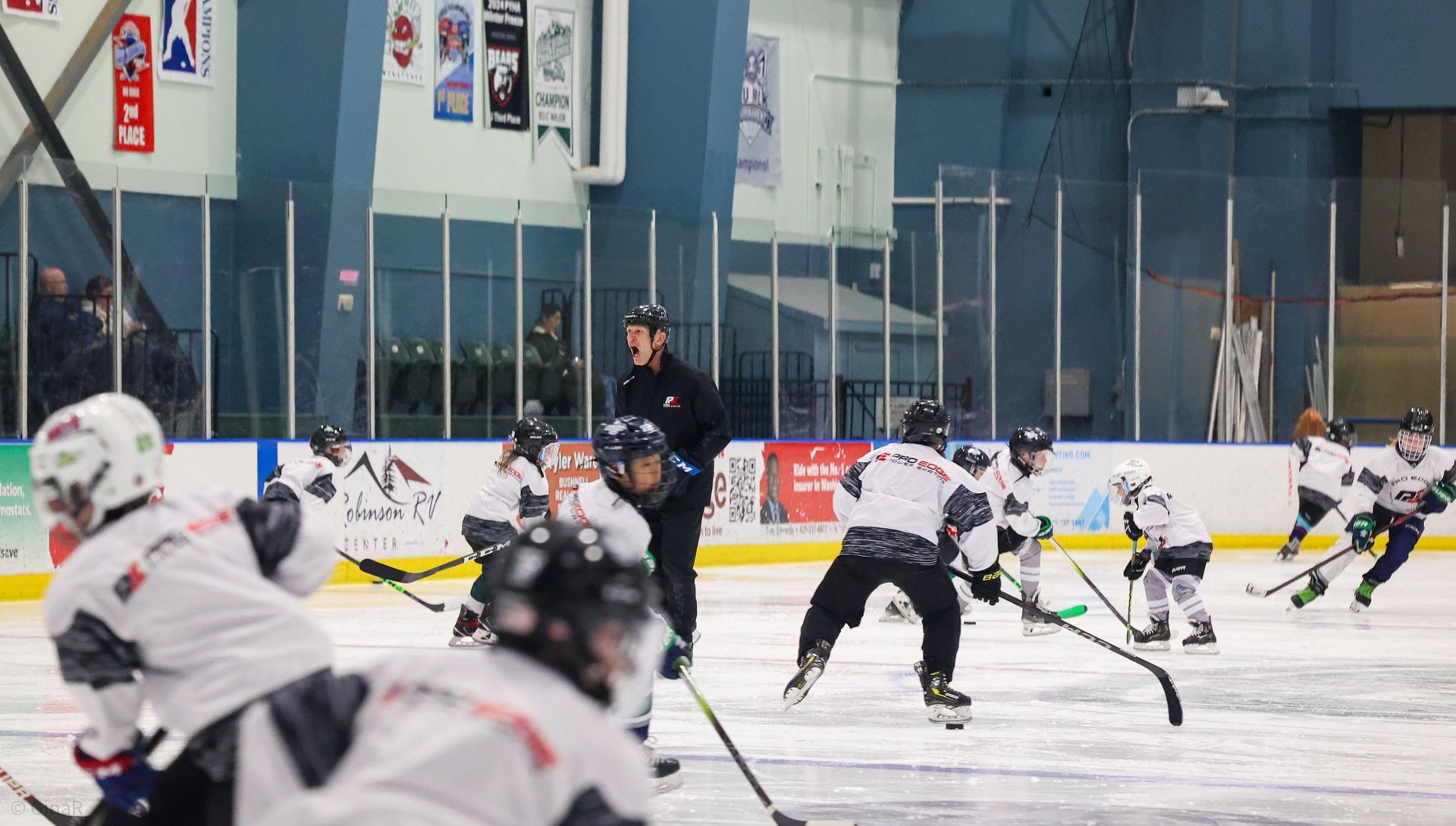 Ice hockey game with players in white and dark jerseys skating on an indoor rink