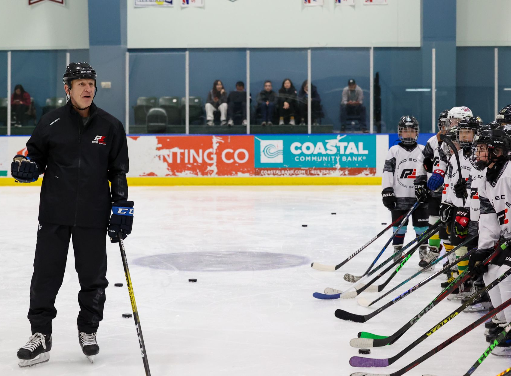 Ice hockey coach addressing lined-up players on an indoor rink during practice
