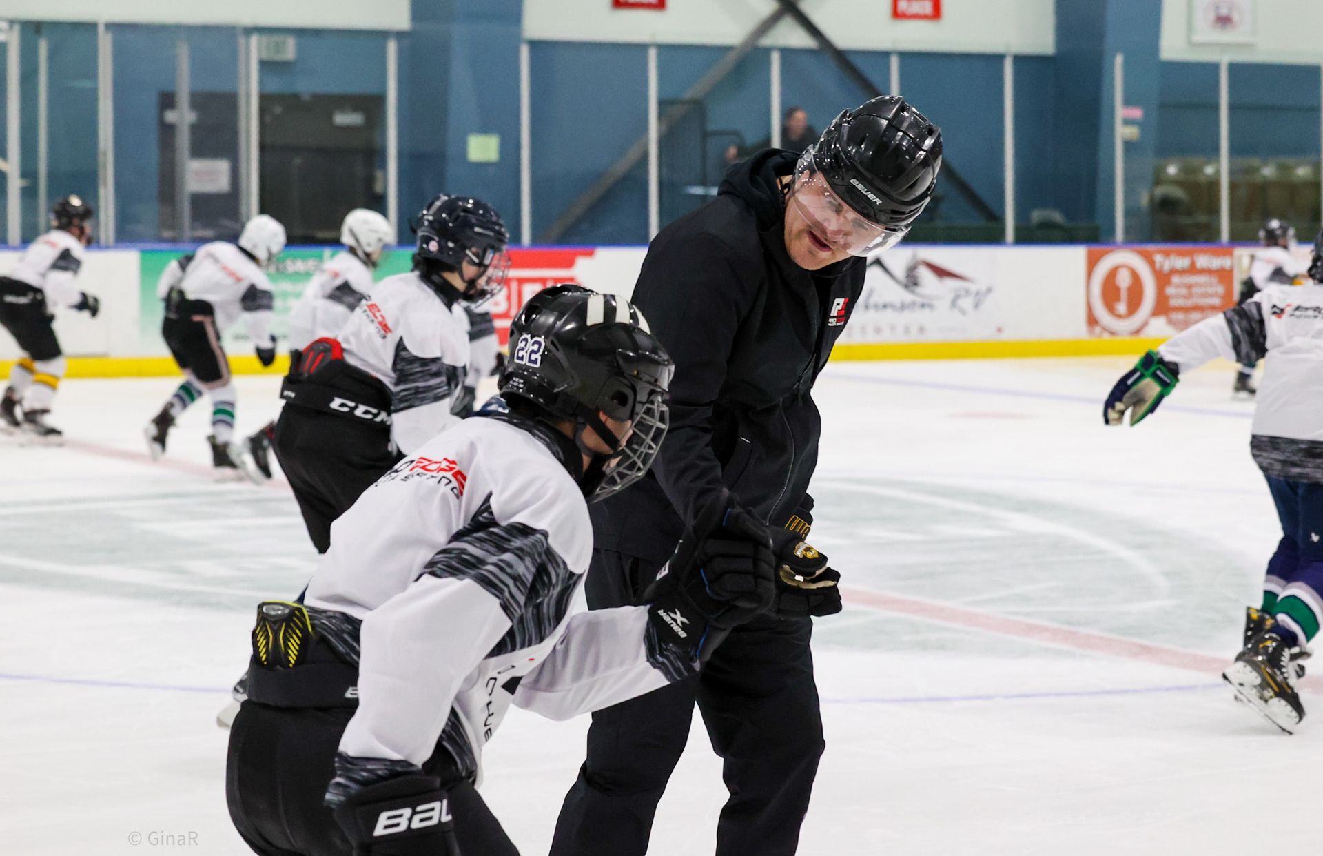 Ice hockey players in black and white jerseys battle for the puck on an indoor rink