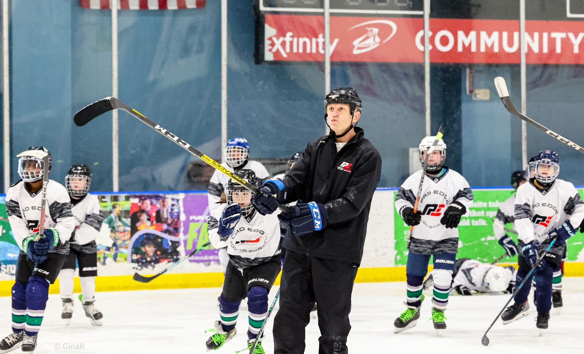 Youth hockey coach instructing players on an indoor ice rink during practice