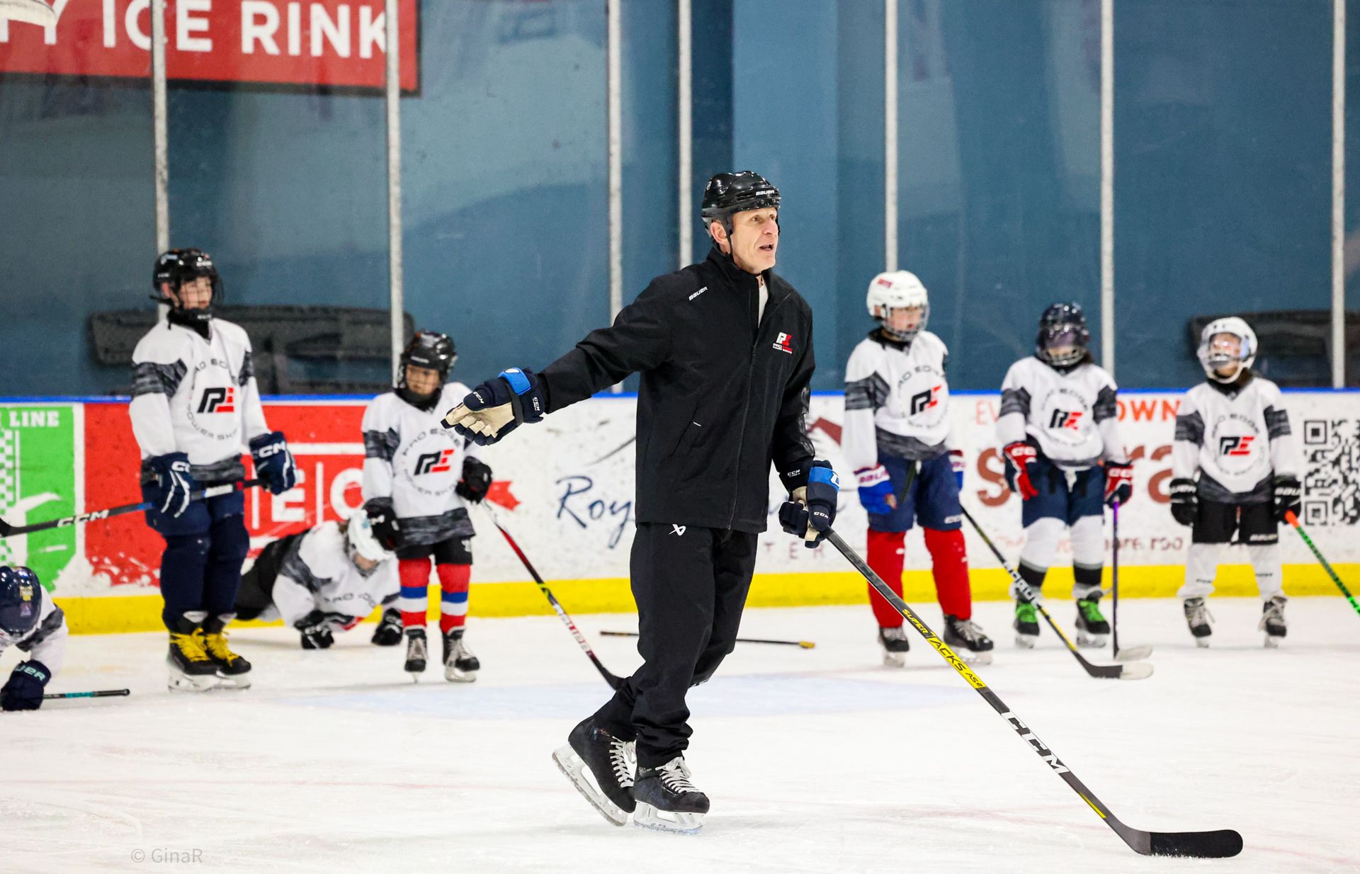 Coach on ice rink guiding young hockey players during practice