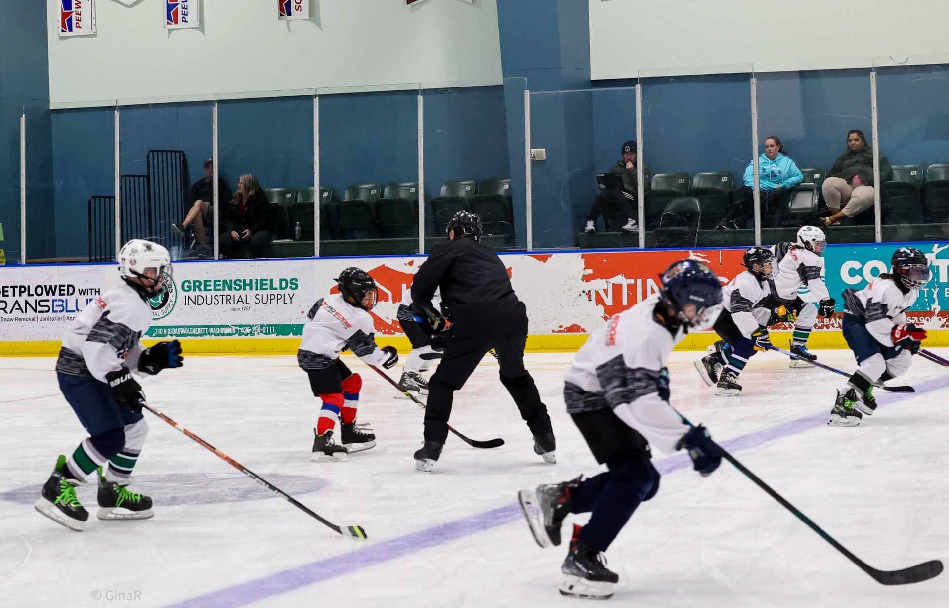 Youth hockey players skating during a game on an indoor ice rink