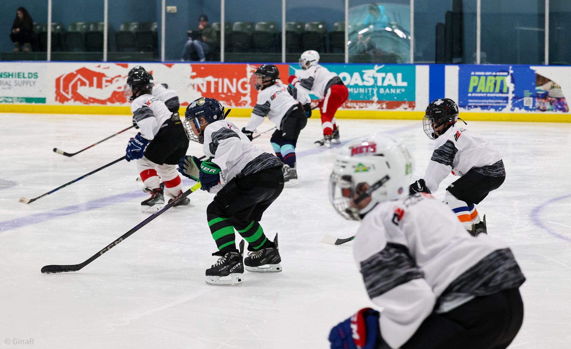 Ice hockey players in white and black uniforms skating hard near the goal during a game