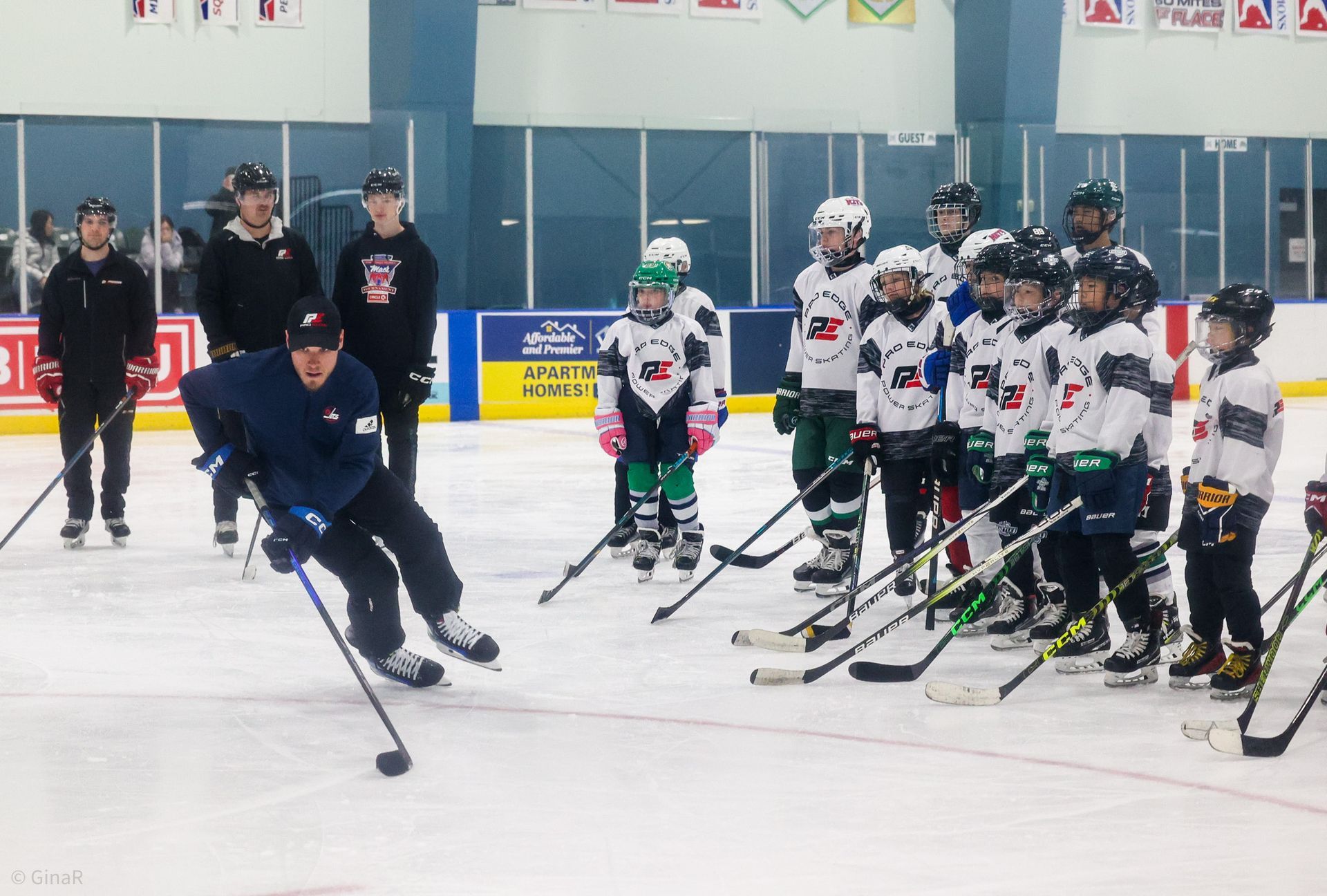 Hockey coach demonstrating a move to youth players on an indoor ice rink