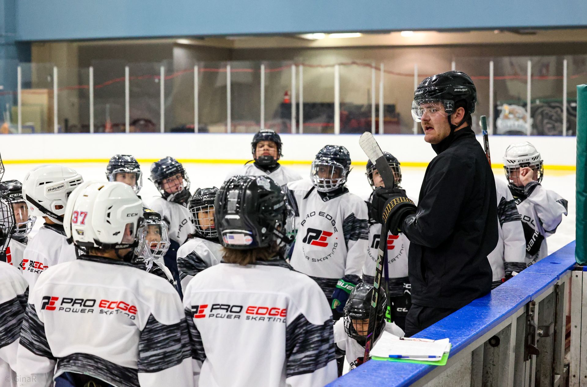 Hockey coach addressing a youth team on the bench during an indoor rink practice