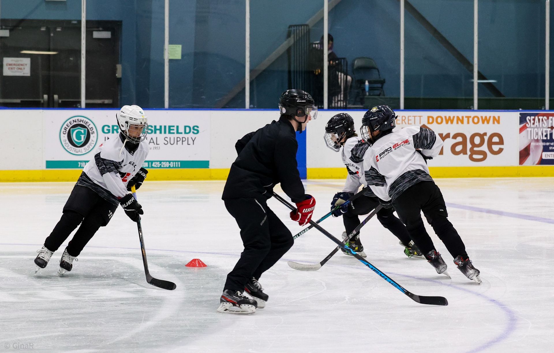 Ice hockey players in black and white jerseys skating and battling for the puck on an indoor rink