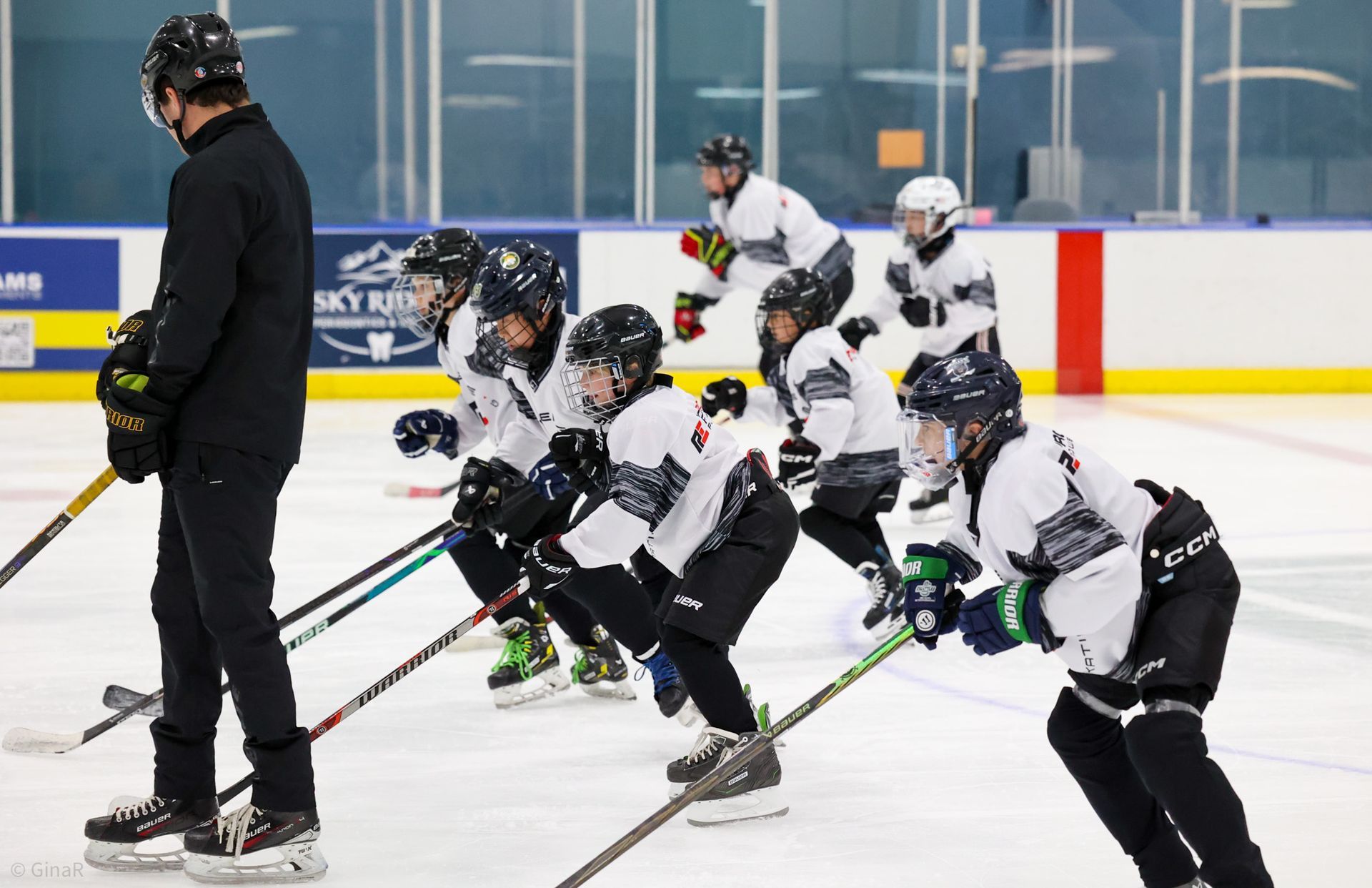 Ice hockey coach watching players do a drill on an indoor rink