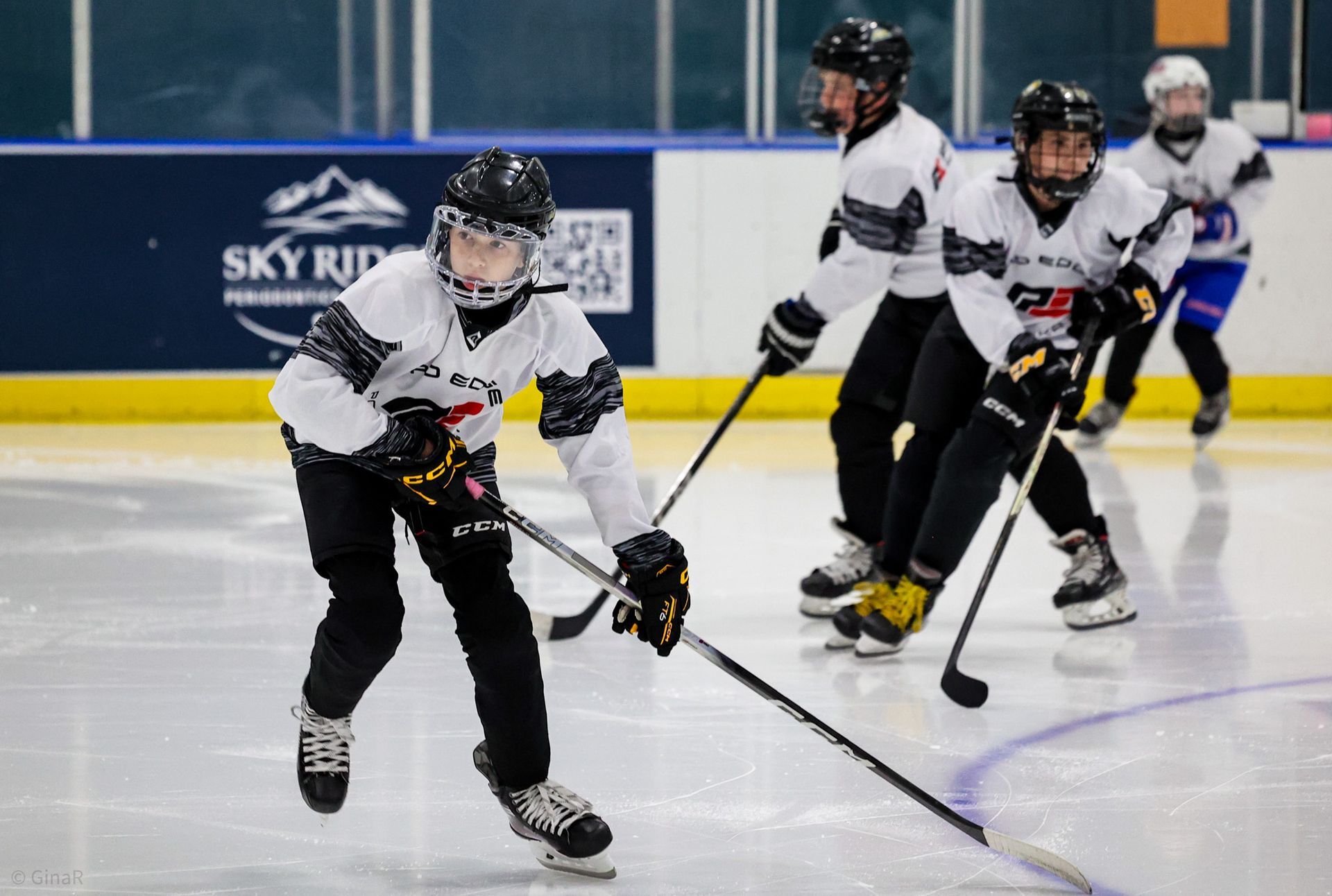 Ice hockey players in white jerseys skating on an indoor rink during a game