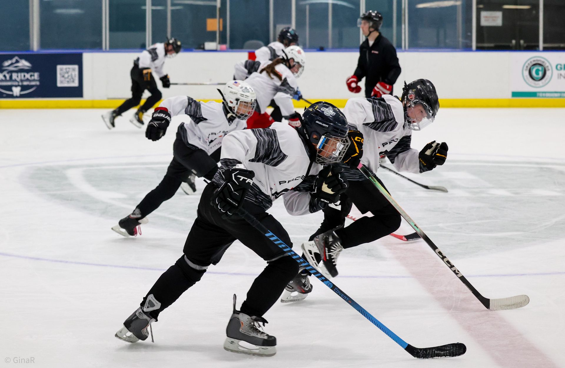 Youth hockey players skating during a faceoff on an indoor ice rink