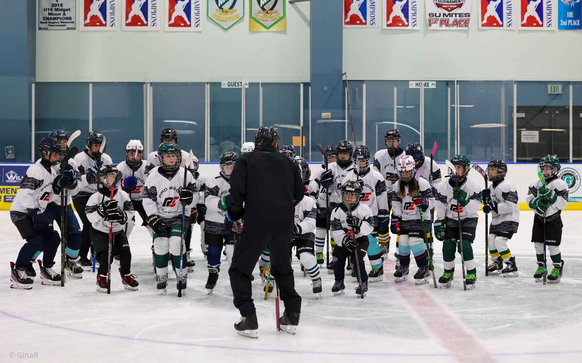 Youth hockey team lined up on an indoor rink with a coach in front of them.
