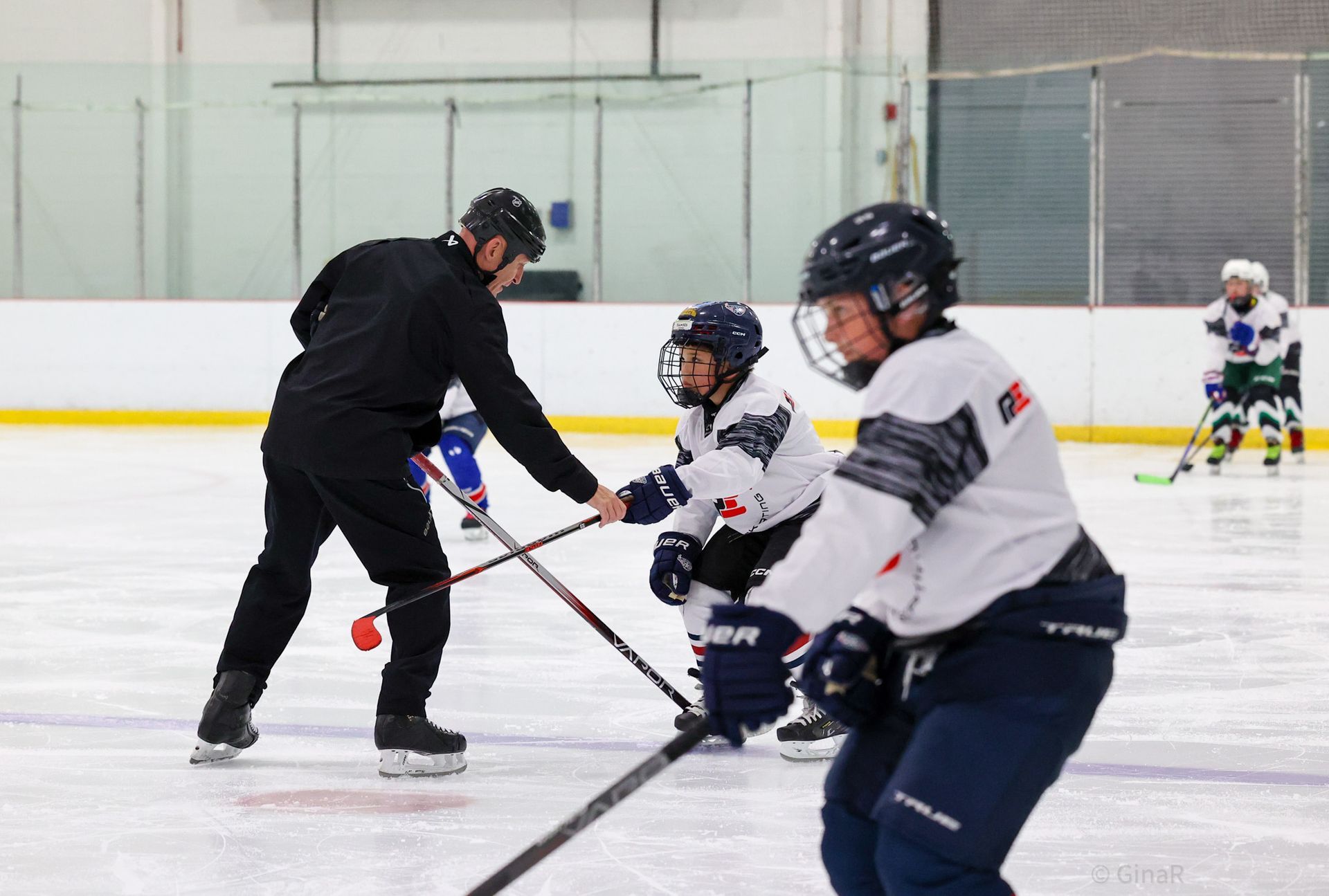 Ice hockey coach instructing child players on an indoor rink during practice