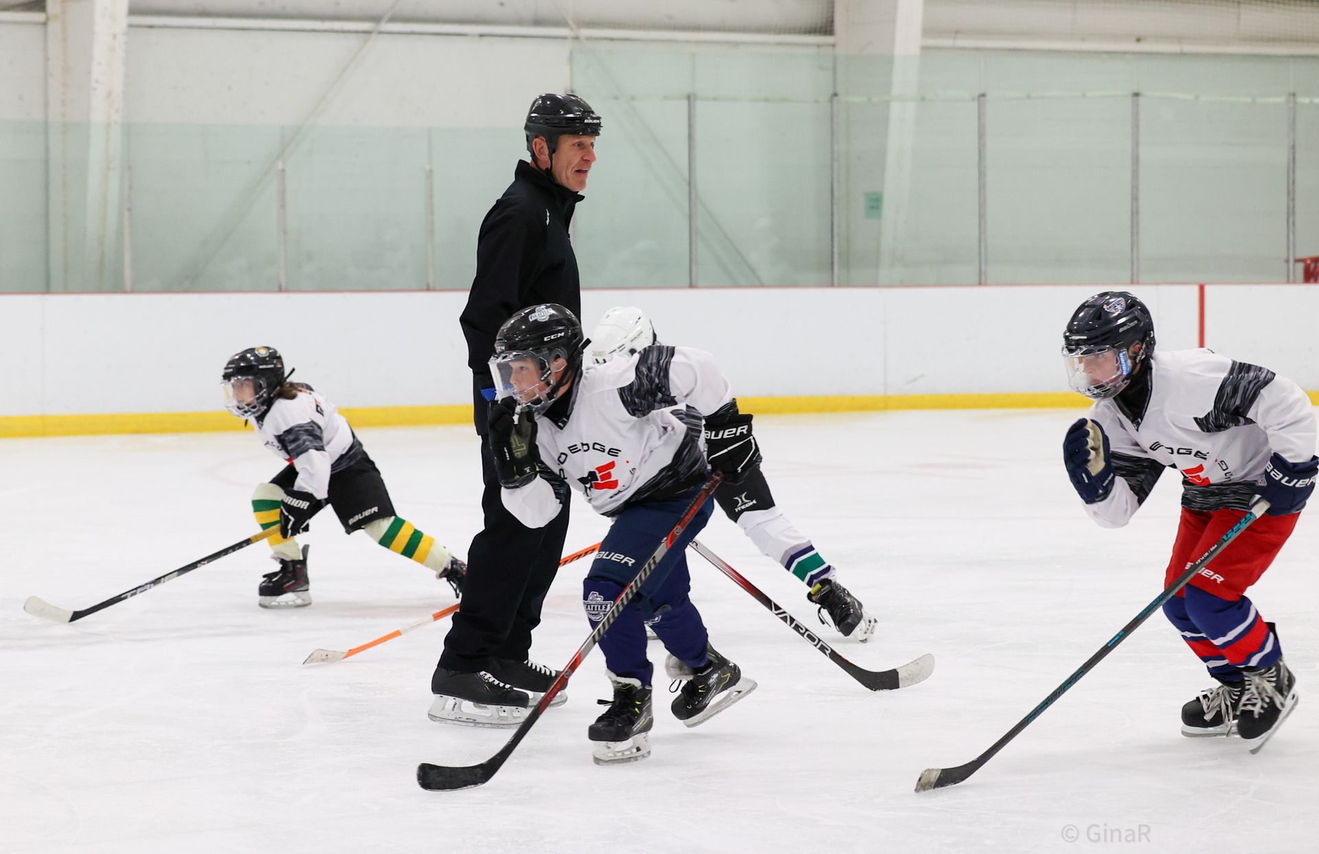 Youth hockey players and coach on an indoor ice rink during practice