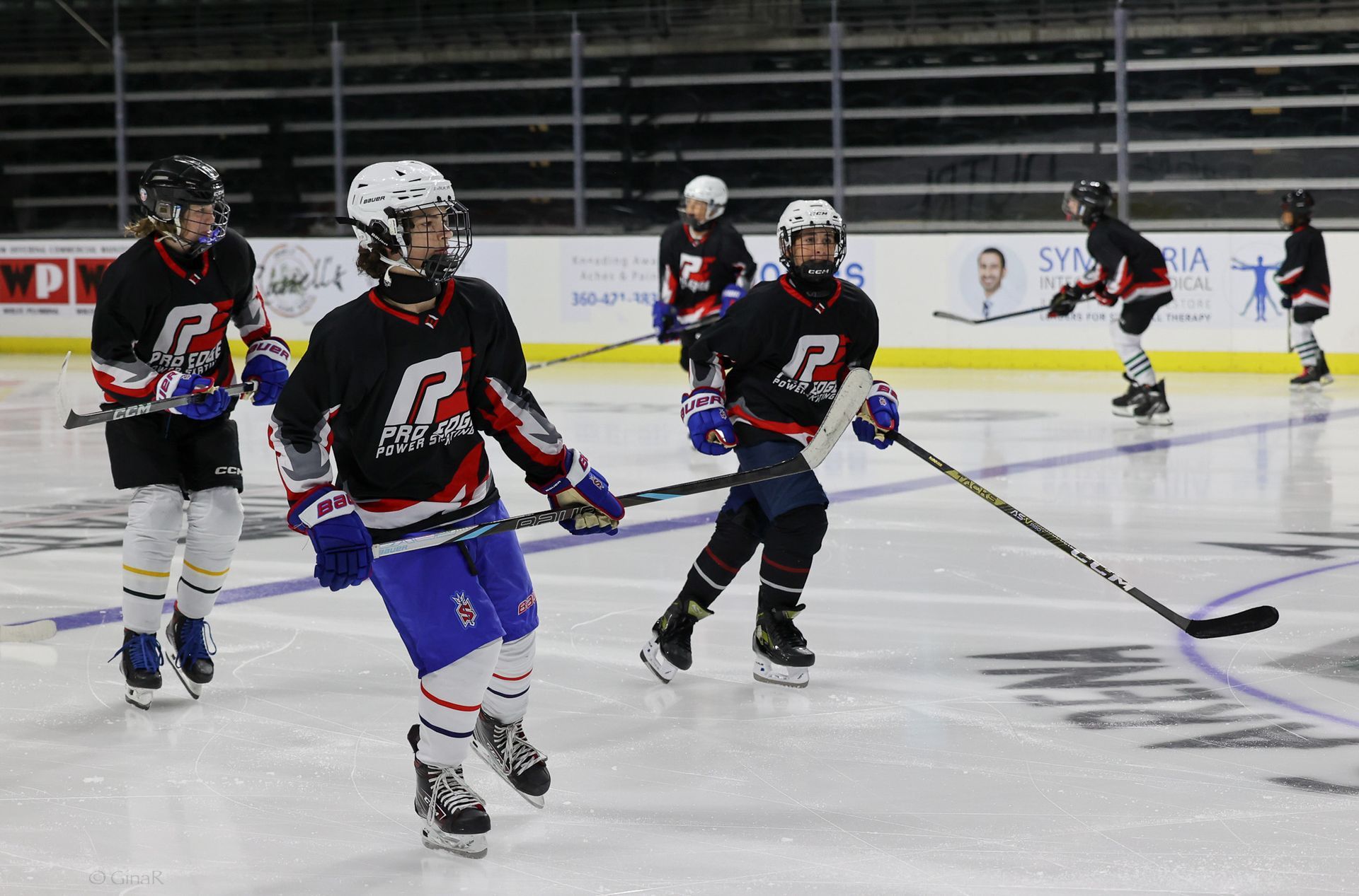 Youth hockey players in black jerseys skating on an ice rink during practice or a game