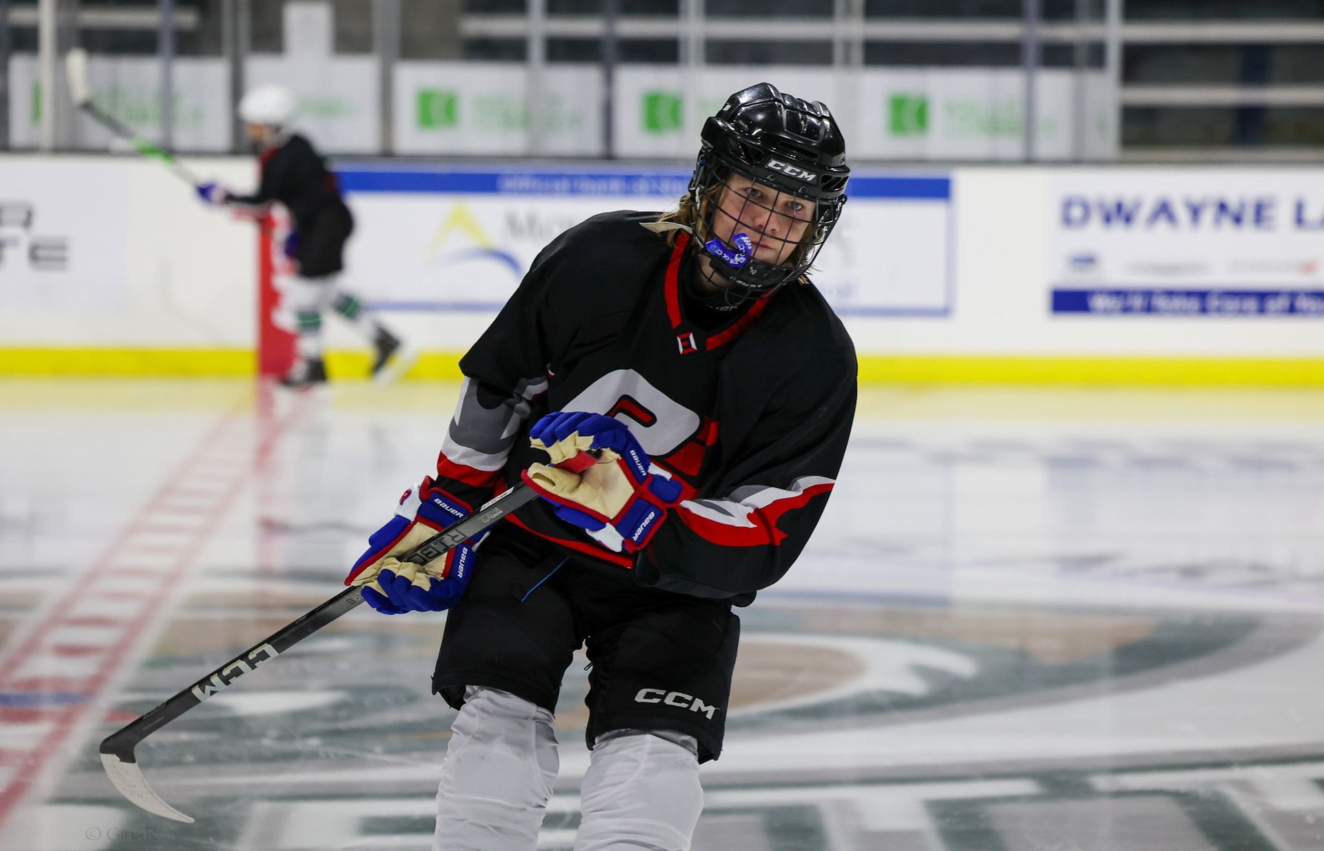 Ice hockey player in black jersey skating with puck on an indoor rink