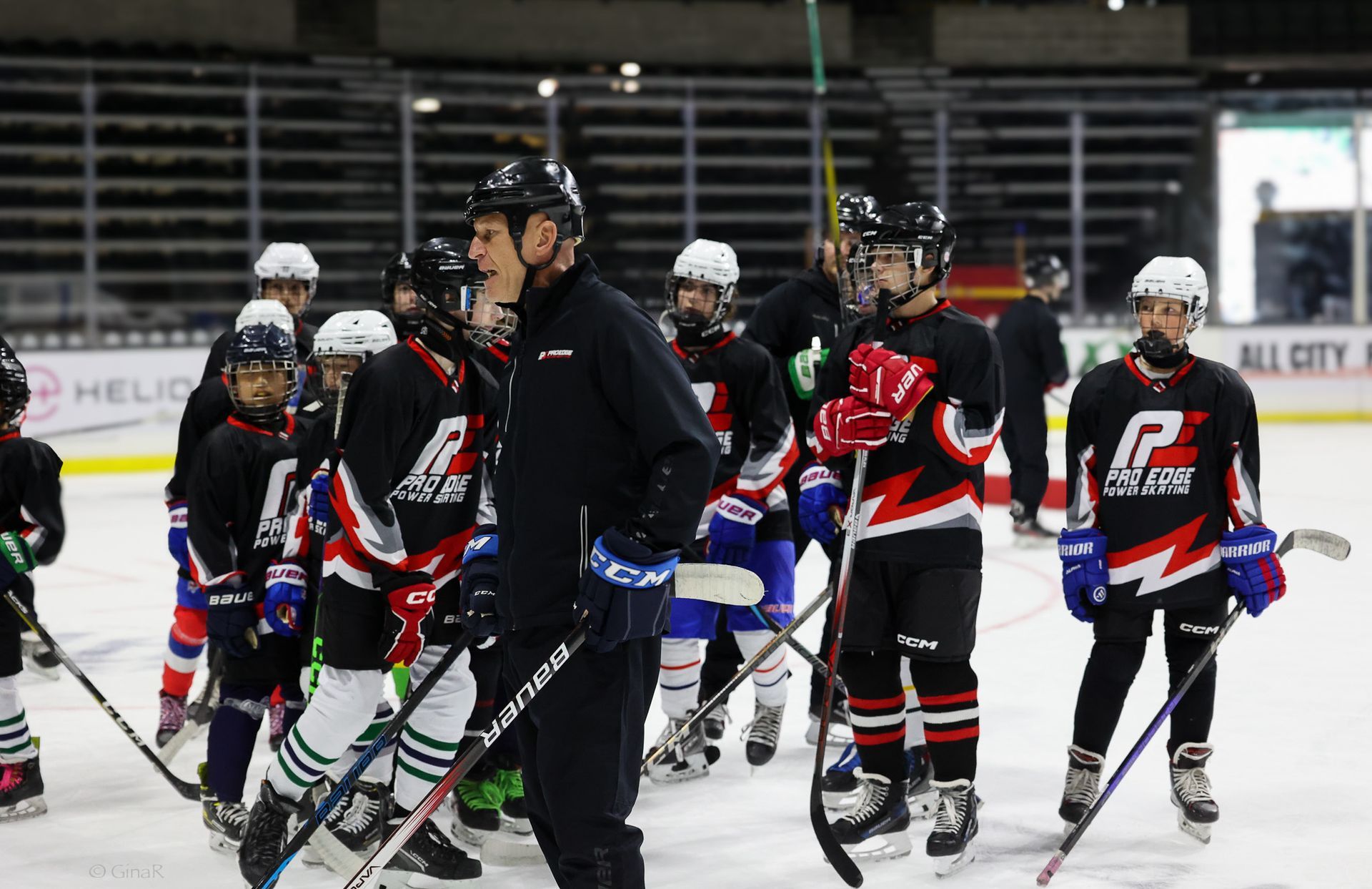 Youth hockey players and a coach standing on an ice rink in black, red, and white uniforms