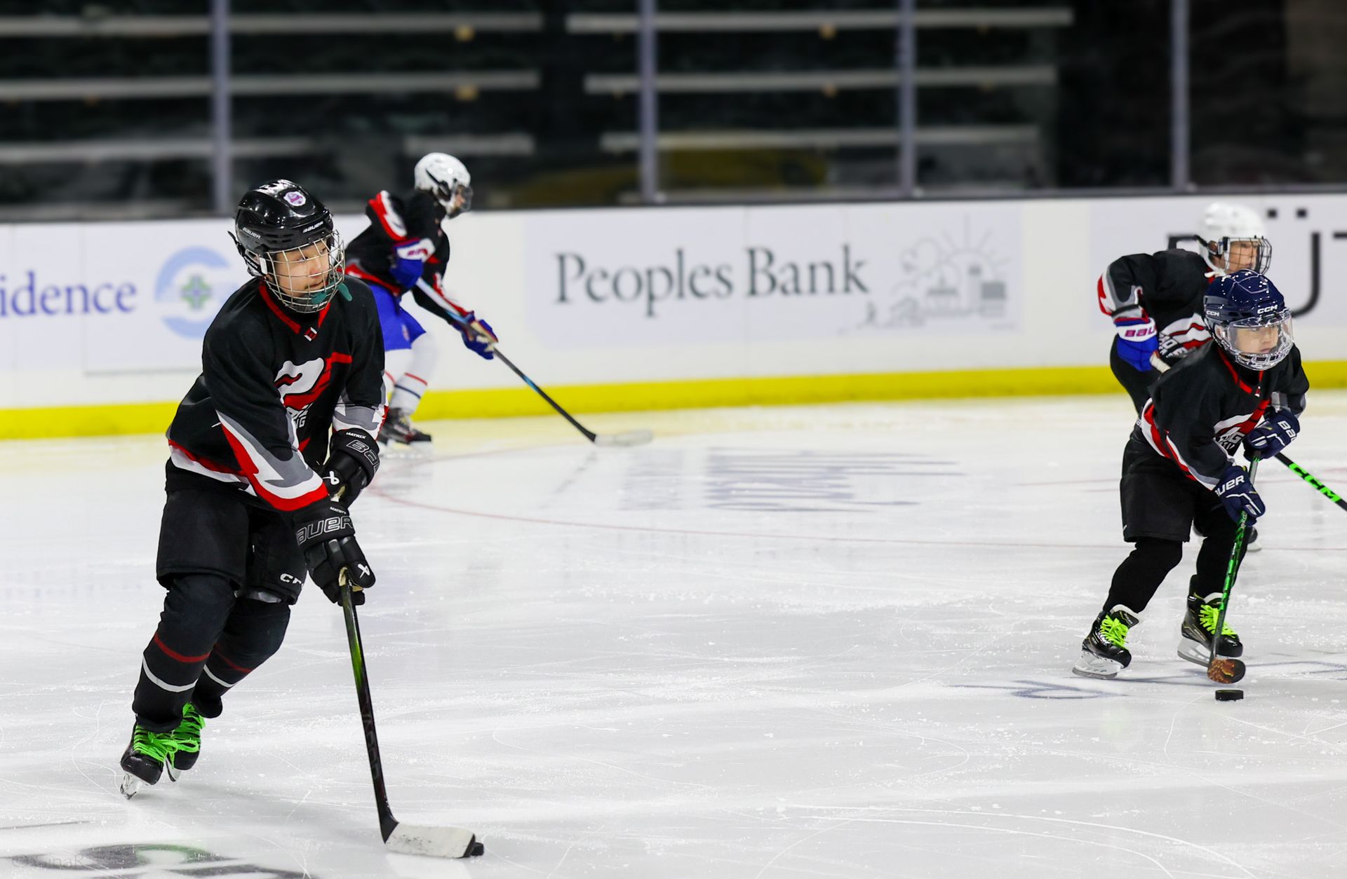 Ice hockey players in black and red uniforms skating on an indoor rink during a game