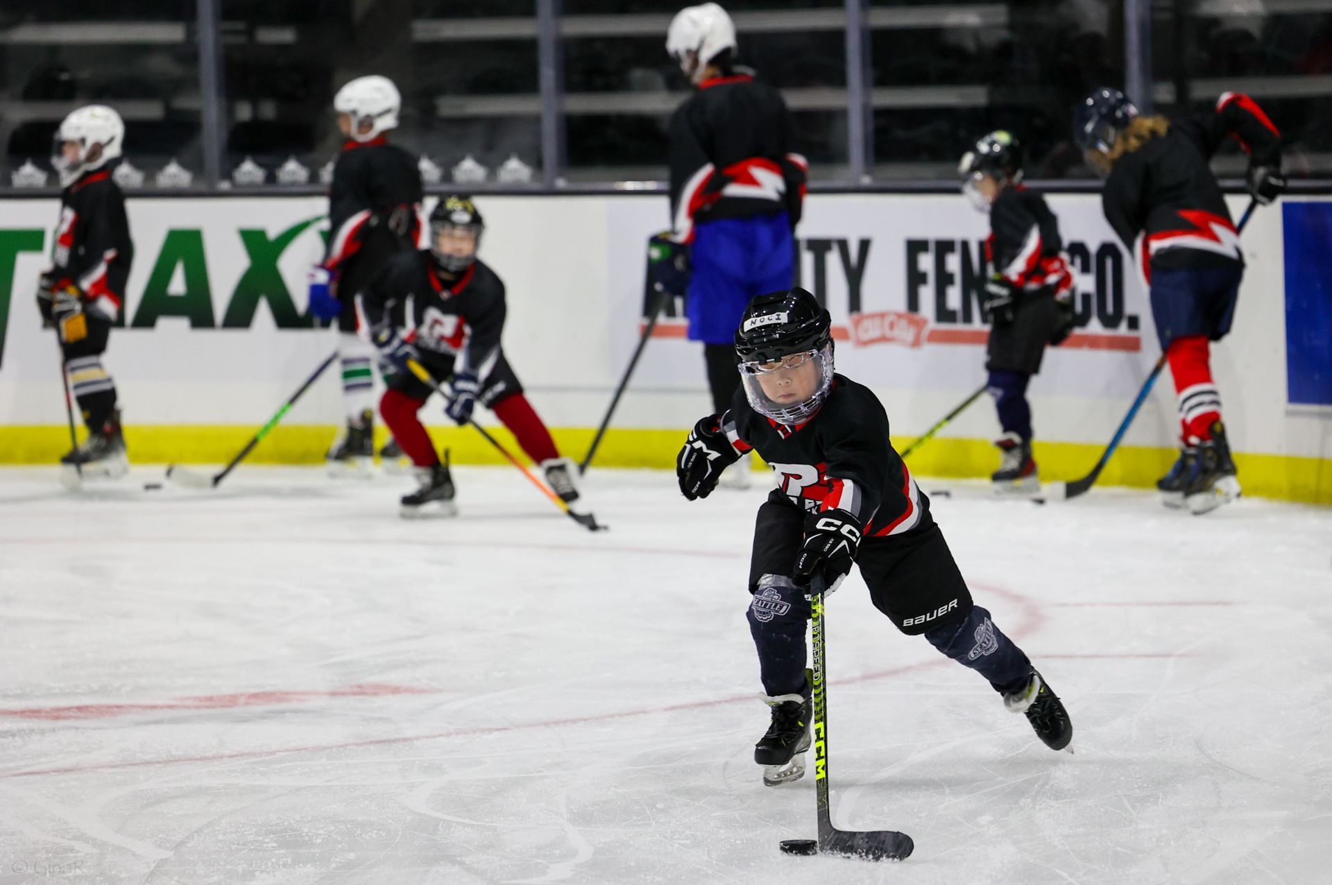 Youth hockey players skating on an indoor ice rink during practice or a game.