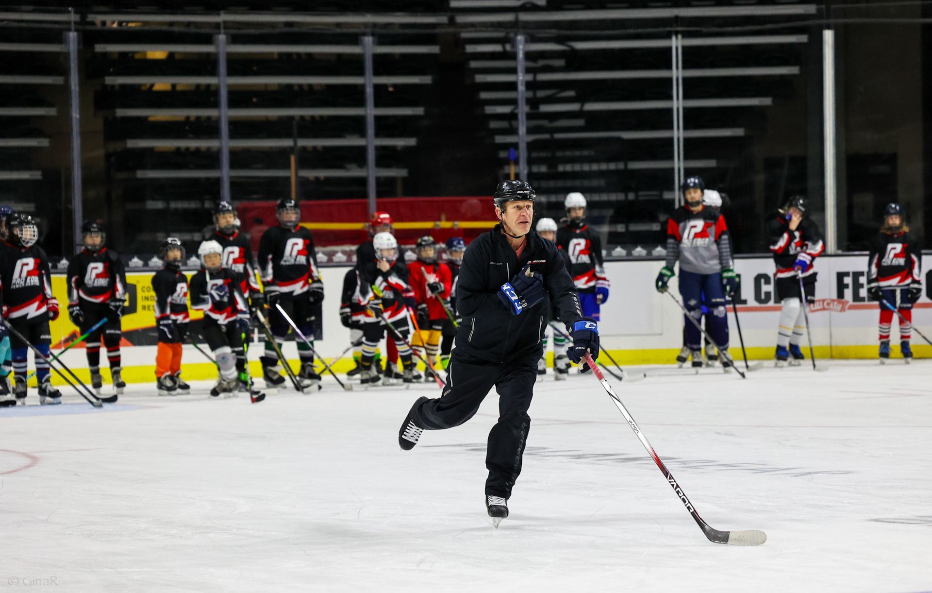 Ice hockey player skating on rink with teammates lined up in the background